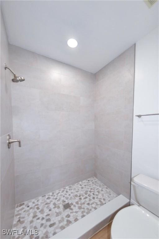 bathroom featuring toilet and a tile shower