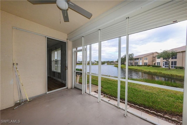 unfurnished sunroom featuring a water view and ceiling fan