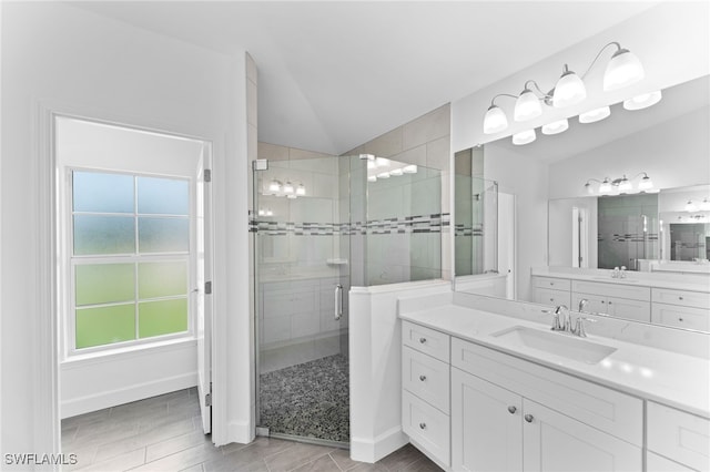 bathroom featuring walk in shower, vaulted ceiling, and vanity