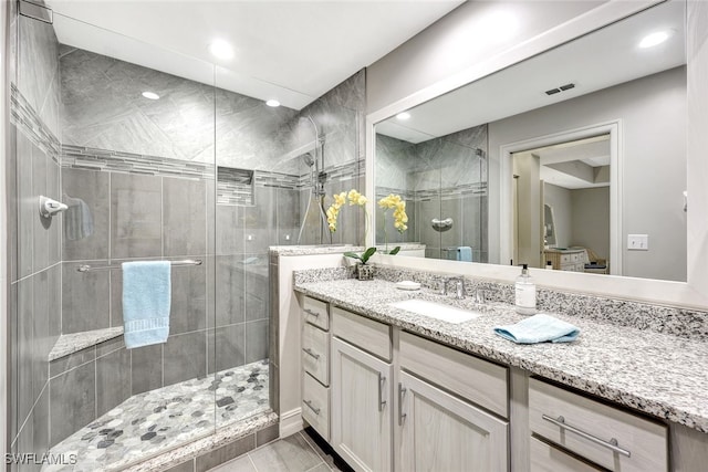 bathroom featuring a shower with shower door and vanity