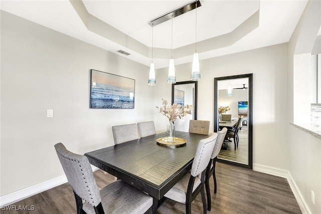 dining area with ceiling fan, dark hardwood / wood-style floors, and a tray ceiling