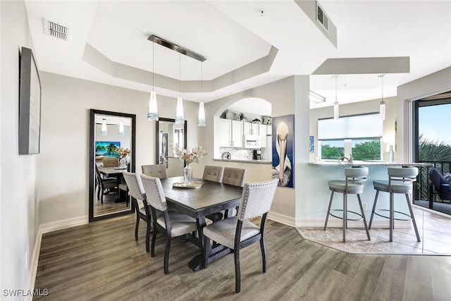 dining space with a raised ceiling and hardwood / wood-style floors