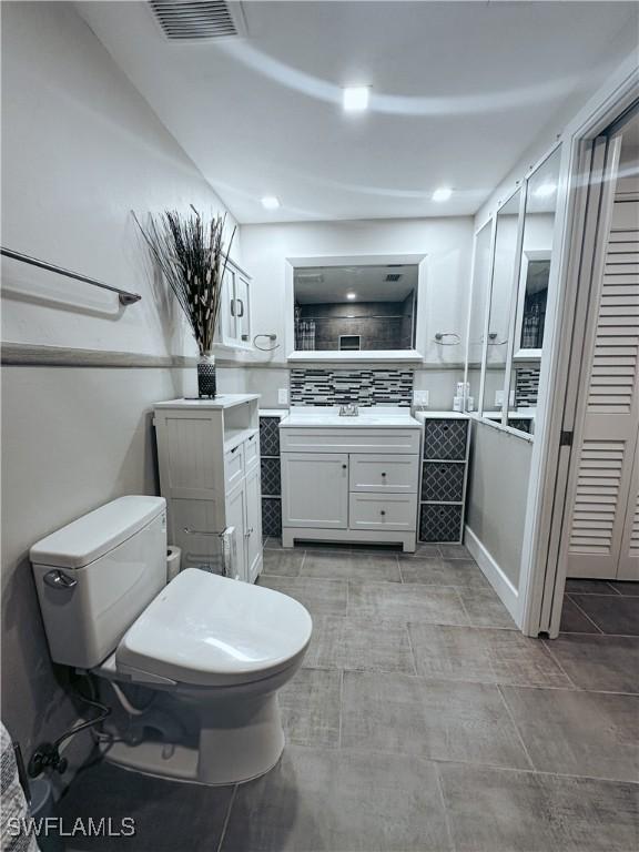 bathroom featuring backsplash, toilet, and vanity