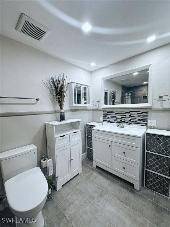 full bathroom with toilet, visible vents, backsplash, and vanity