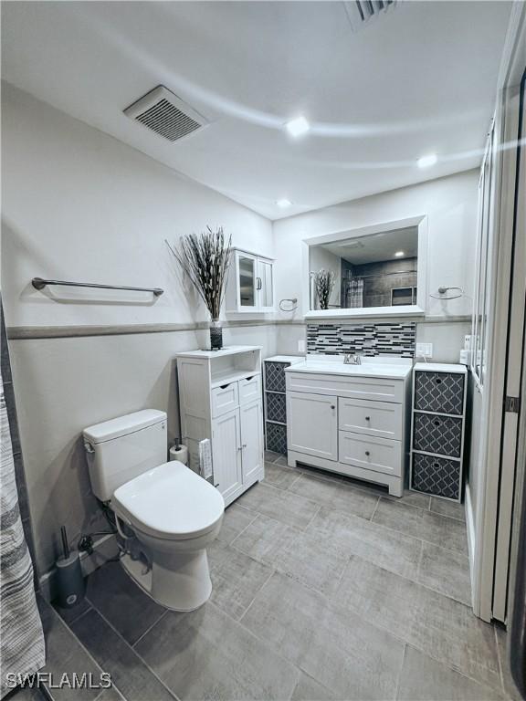 bathroom with toilet, decorative backsplash, and vanity