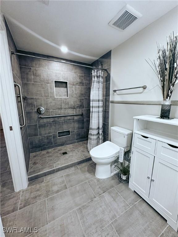 bathroom with toilet, vanity, a shower stall, and visible vents