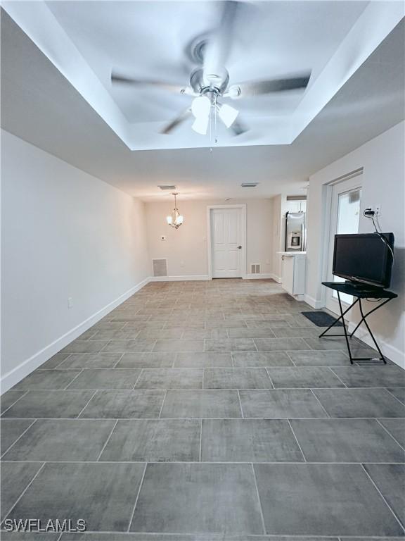 unfurnished living room with ceiling fan with notable chandelier