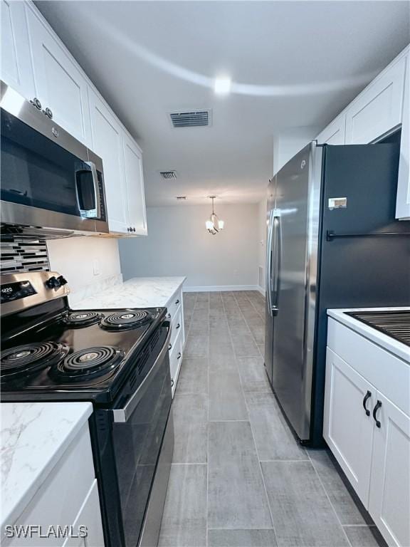 kitchen with light stone countertops, white cabinets, hanging light fixtures, and appliances with stainless steel finishes