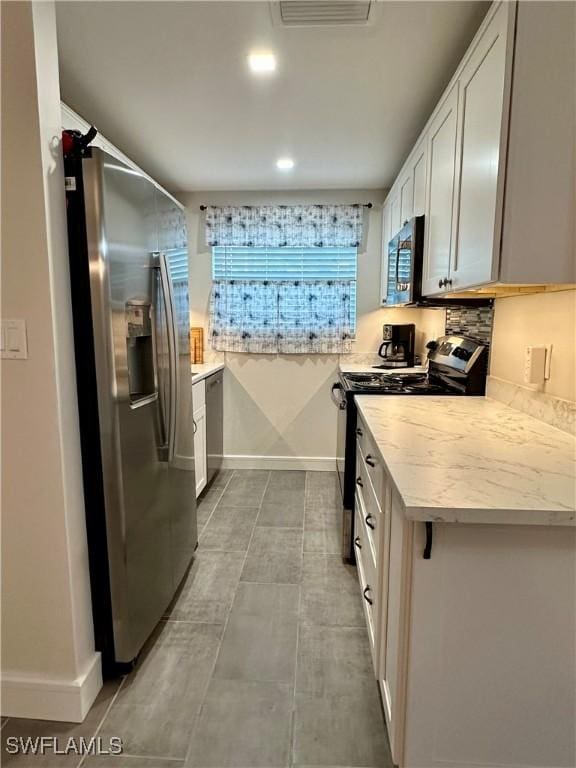 kitchen with white cabinets, stainless steel appliances, and light stone countertops