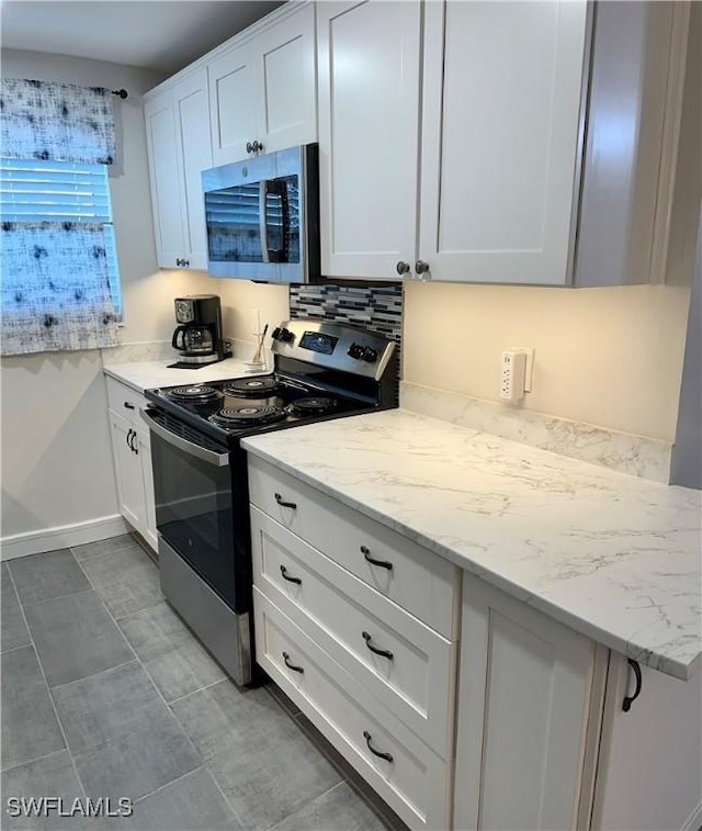 kitchen featuring white cabinets, tasteful backsplash, light tile patterned floors, light stone counters, and stainless steel appliances