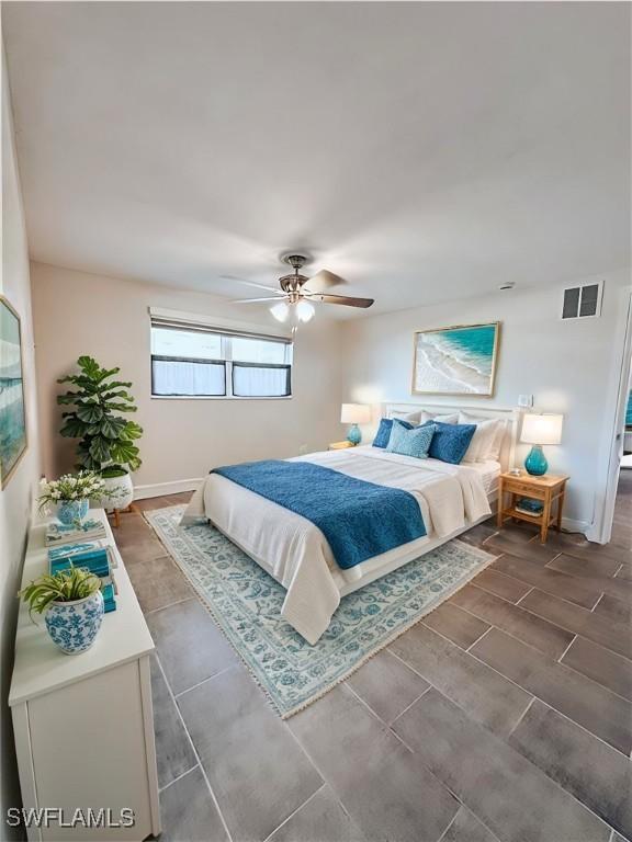 bedroom featuring ceiling fan, visible vents, baseboards, and wood finish floors