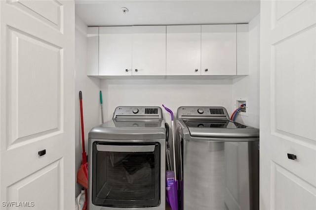 clothes washing area with cabinets and washing machine and dryer