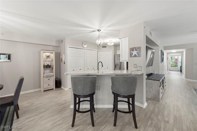 kitchen with light wood-type flooring, a breakfast bar area, white cabinets, and kitchen peninsula