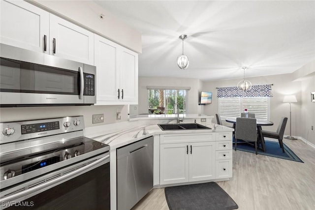 kitchen featuring appliances with stainless steel finishes, white cabinetry, hanging light fixtures, and sink