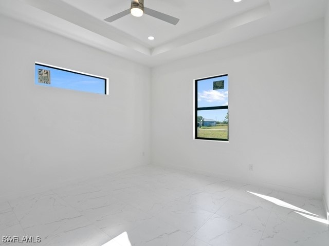 empty room featuring a tray ceiling and ceiling fan