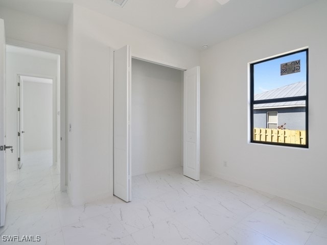 unfurnished bedroom with ceiling fan and a closet