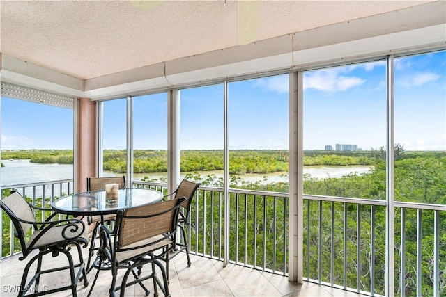 sunroom featuring a water view