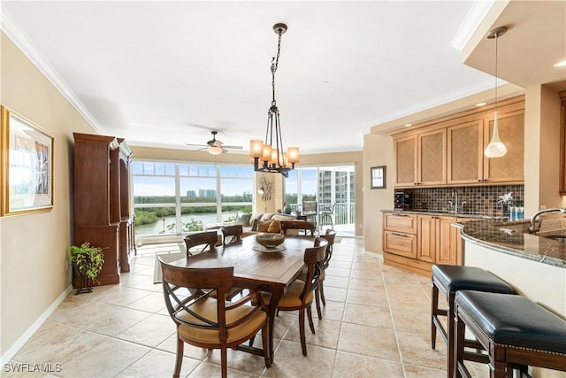 tiled dining room with a water view, sink, ceiling fan with notable chandelier, and ornamental molding