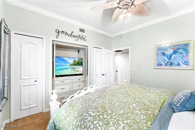 carpeted bedroom featuring ceiling fan, two closets, and crown molding