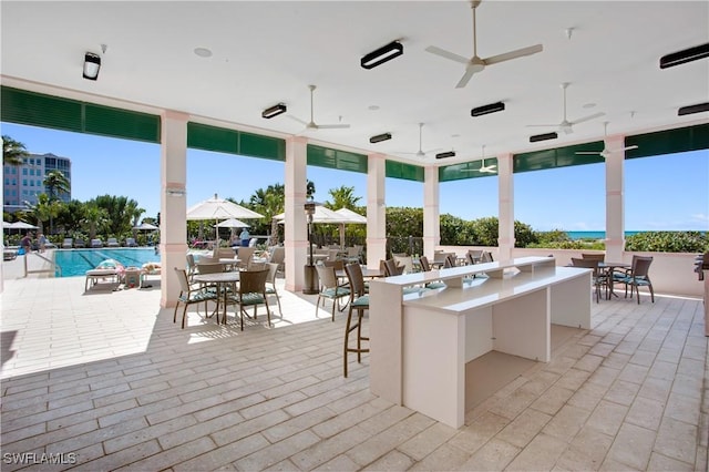 view of patio featuring ceiling fan, an outdoor bar, and a community pool