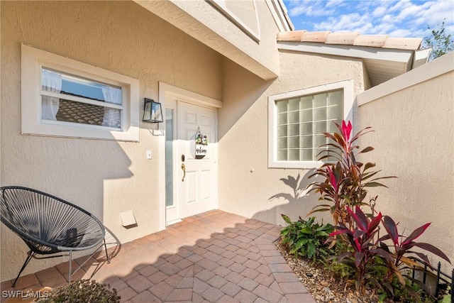 entrance to property featuring a patio and stucco siding