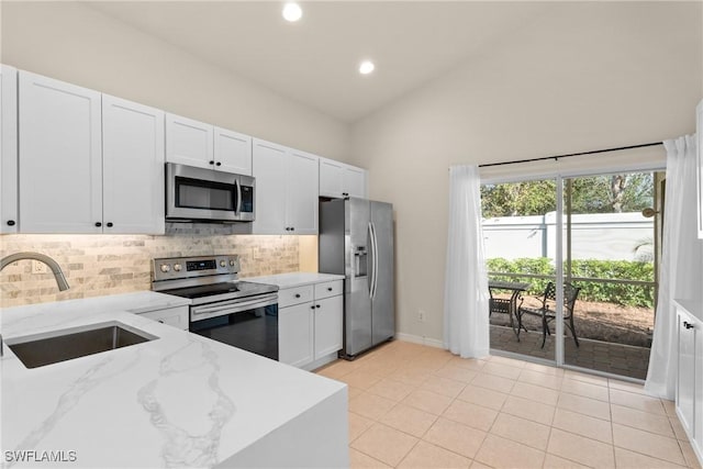 kitchen featuring stainless steel appliances, sink, white cabinetry, decorative backsplash, and light stone countertops