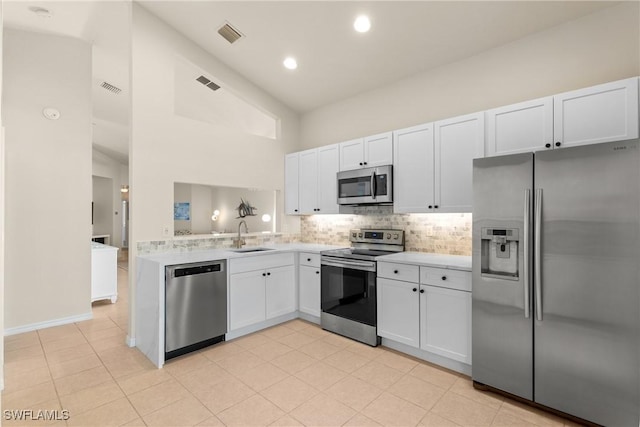 kitchen with kitchen peninsula, stainless steel appliances, sink, and white cabinetry