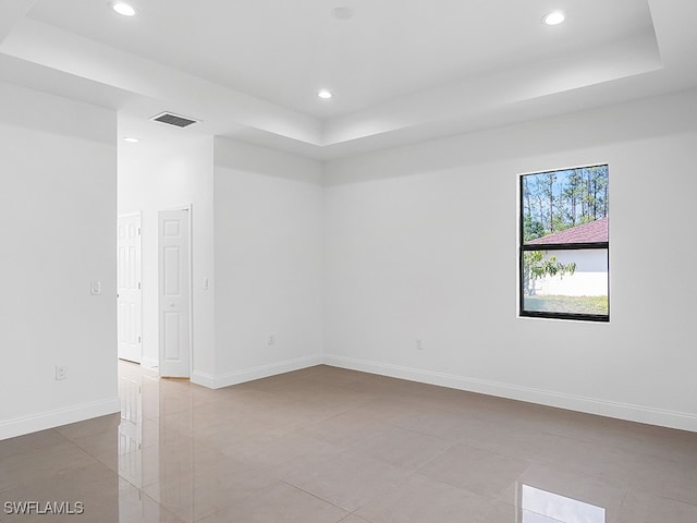 tiled spare room with a tray ceiling