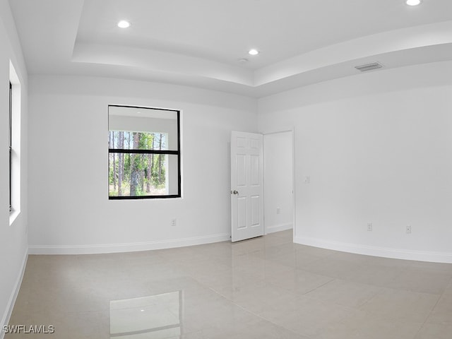 tiled spare room with a raised ceiling