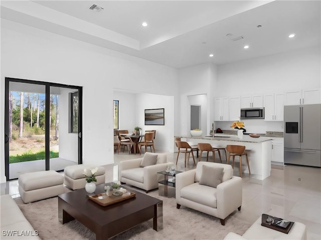 tiled living room featuring sink and a towering ceiling