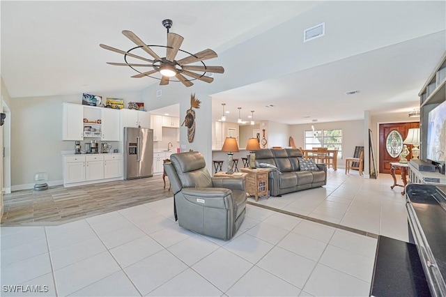 tiled living room featuring ceiling fan, sink, and vaulted ceiling