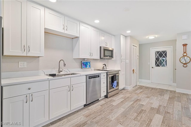 kitchen with sink, light hardwood / wood-style floors, white cabinetry, and appliances with stainless steel finishes