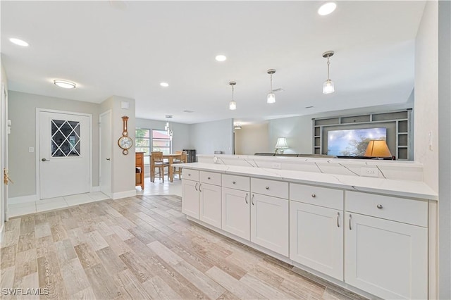 kitchen featuring pendant lighting, white cabinets, built in shelves, light stone counters, and light hardwood / wood-style flooring