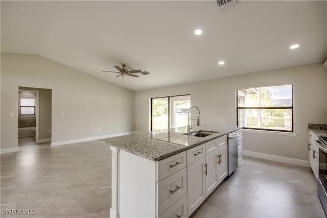 kitchen with an island with sink, appliances with stainless steel finishes, vaulted ceiling, light stone counters, and sink