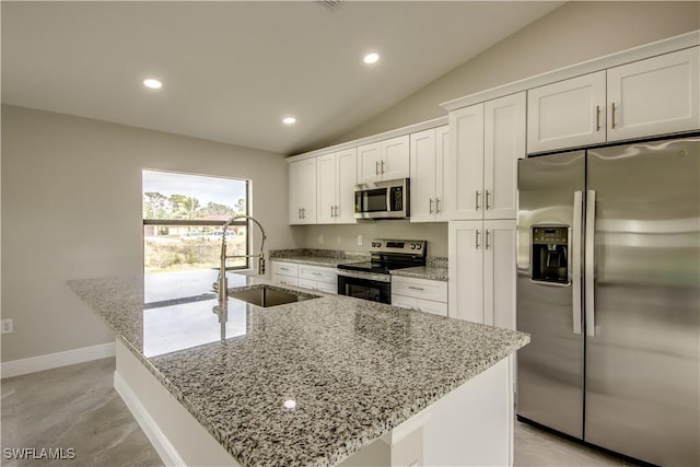 kitchen featuring white cabinetry, an island with sink, appliances with stainless steel finishes, vaulted ceiling, and sink