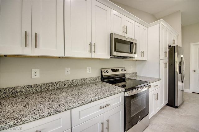 kitchen featuring white cabinets, light stone countertops, light tile patterned floors, and stainless steel appliances