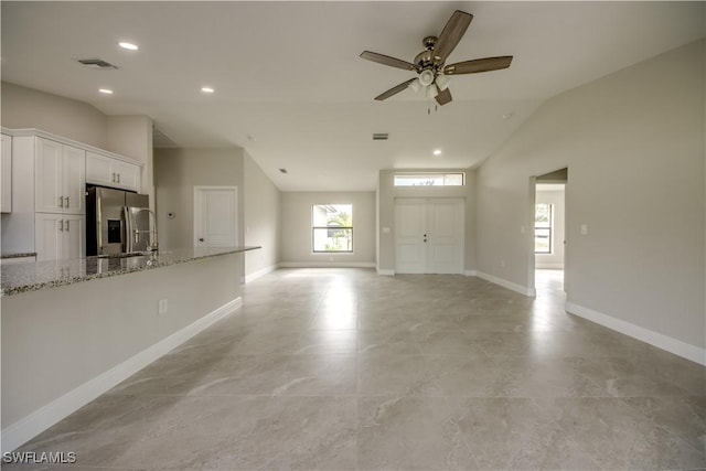 unfurnished living room with ceiling fan, sink, and vaulted ceiling