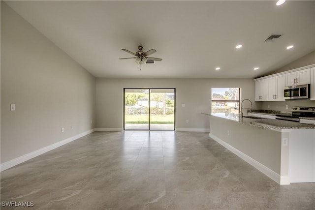 kitchen with white cabinetry, ceiling fan, appliances with stainless steel finishes, light stone counters, and sink