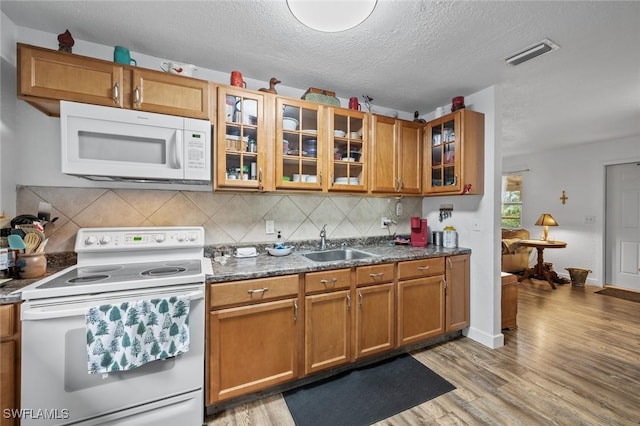 kitchen featuring white appliances, a textured ceiling, tasteful backsplash, sink, and light wood-type flooring