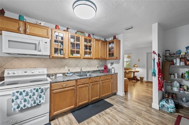 kitchen with light hardwood / wood-style floors, backsplash, white appliances, a textured ceiling, and sink