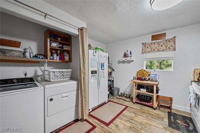 laundry room with light wood-type flooring, independent washer and dryer, and a textured ceiling