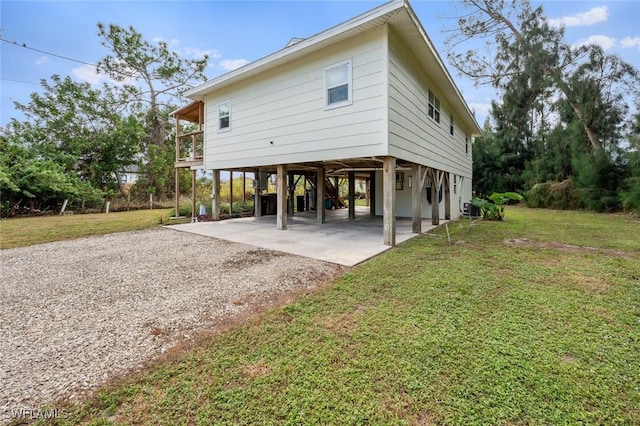 back of house featuring central AC, a carport, and a lawn