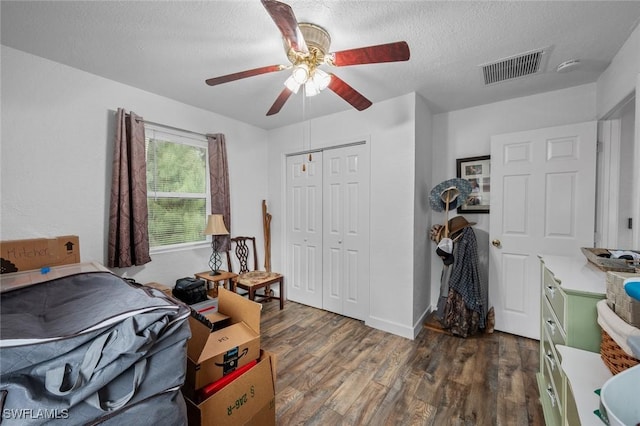 bedroom with ceiling fan, a closet, dark hardwood / wood-style flooring, and a textured ceiling