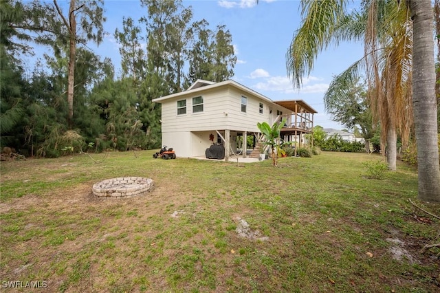 back of property with a lawn, an outdoor fire pit, and a wooden deck