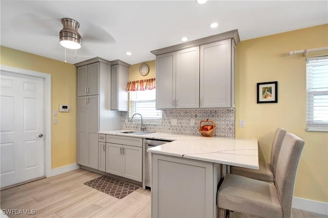 kitchen with sink, stainless steel dishwasher, gray cabinets, and kitchen peninsula