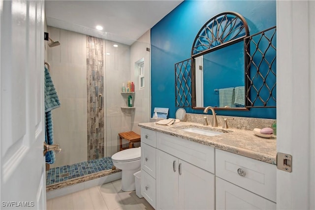 bathroom featuring toilet, a shower with shower door, and vanity