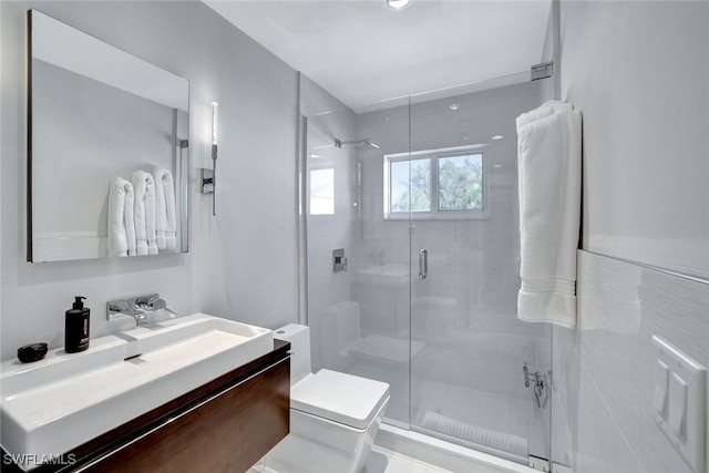 bathroom featuring vanity, a shower with shower door, and toilet