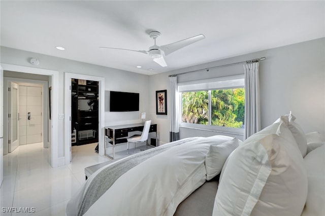 tiled bedroom with a walk in closet, ceiling fan, and a closet