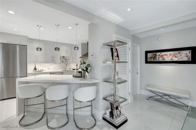 kitchen with pendant lighting, stainless steel fridge, white cabinetry, a kitchen breakfast bar, and decorative backsplash