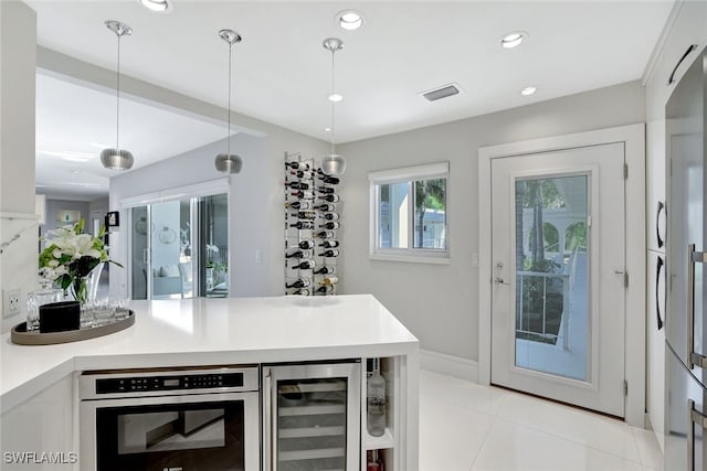 bar featuring hanging light fixtures, beverage cooler, white cabinets, and light tile patterned flooring